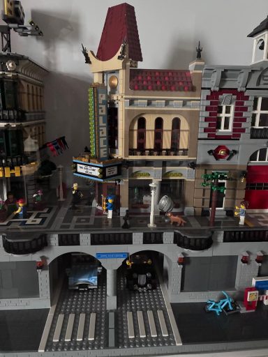 Stedelijke LEGO-scène met een bioscoop, winkels en auto's in een straat.